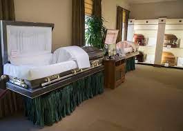 A showroom displaying several caskets of various colors and materials. The setting is calm and formal, with soft lighting and neatly arranged displays.