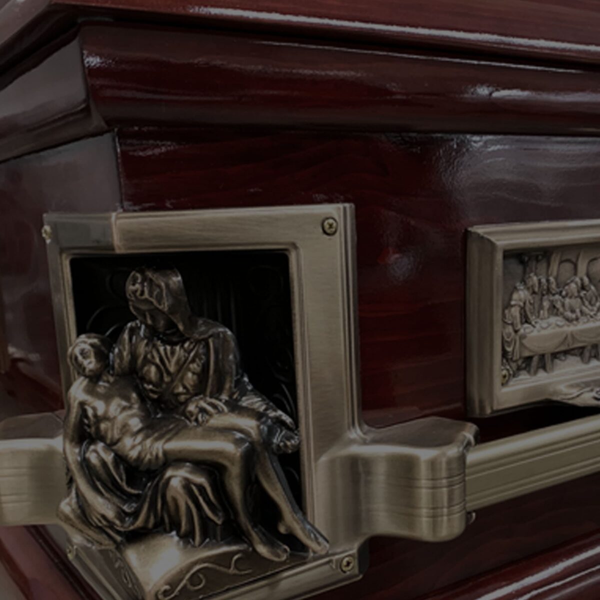 A polished wooden casket with ornate bronze detailing, featuring a bas-relief sculpture depicting a peaceful, somber scene, conveying a sense of reverence.